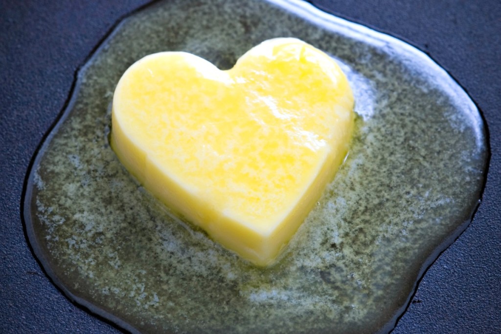 a heart shaped butter pat melting on a non-stick surface